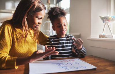 Happy young girl learning to calculate with mother at home, black woman and child